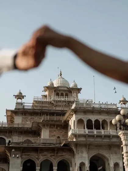 A symbolic shot in front of the Albert Hall Museum in Jaipur. The couple's hands are joined in the foreground, creating a frame that beautifully captures the magnificent architecture behind them, symbolizing their united future.