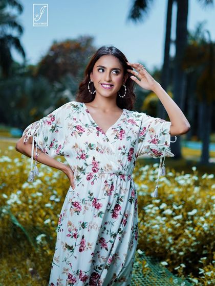 A close-up portrait capturing the model's joyful expression amidst a field of white flowers, highlighting the fresh and vibrant feel of the collection.