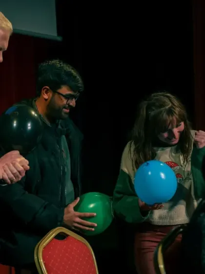 The moment of revelation during my blindfold act at The Magic Circle. The audience members are reacting as I correctly guess the color of the balloon they are holding.