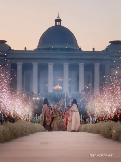The bride's procession makes its way down the grand aisle, illuminated by fireworks. The entire scene is designed to feel like a fairytale, with the palace as the castle.