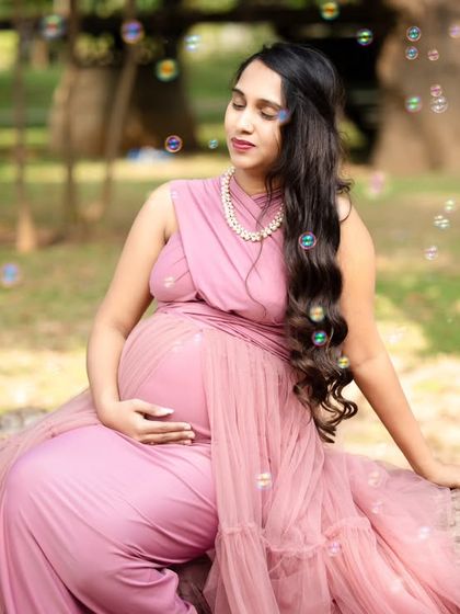 A dreamy outdoor maternity photo. The soft pink gown and the gentle bubbles create a whimsical and magical atmosphere, perfect for celebrating this special time.