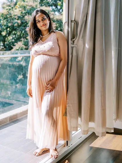 Standing by the balcony door, this mother-to-be is bathed in natural light. It's a simple, elegant portrait that highlights her beautiful silhouette and the peacefulness of the moment.