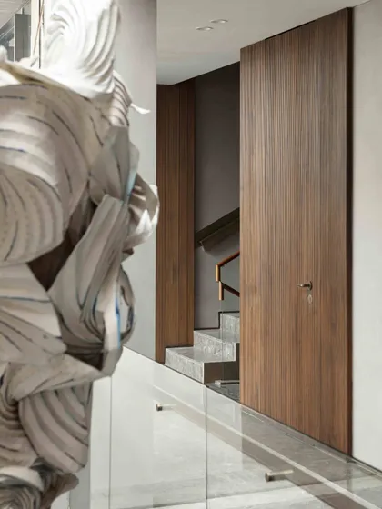 A view of the Bammi Residence staircase, with a large origami installation visible through the glass balustrade. The staircase journey is designed to unfold as a series of artistic and architectural discoveries.