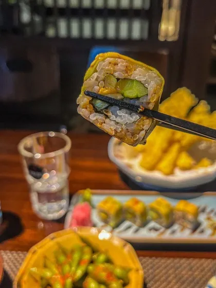A perfect bite of our vegetarian sushi, held by chopsticks. We offer a diverse range of veg and non-veg options, ensuring there is a delightful choice for every palate.