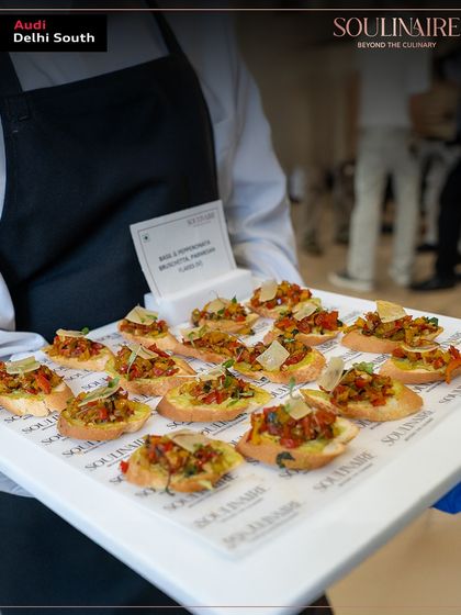 A server presenting a tray of bruschetta with a vibrant topping at the Audi event. Our flying plates service ensures guests can enjoy gourmet bites while mingling.