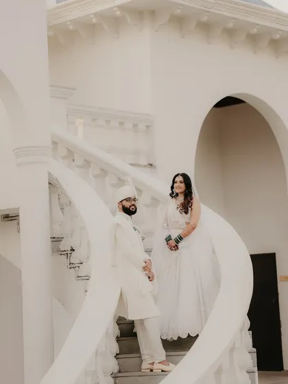 Using the clean, white architecture of the venue to create a stunning portrait. The spiral staircase adds a beautiful leading line, framing the couple in their immaculate white wedding attire.
