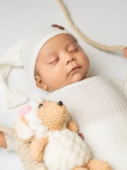 Drifting off to sleep with a cuddly friend. This close-up shot focuses on the peaceful expression of a sleeping newborn during our swing-themed session.