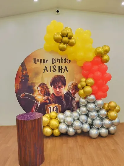 A close-up of the Harry Potter backdrop and balloon garland, showing the personalized "Happy Birthday" message for the event.
