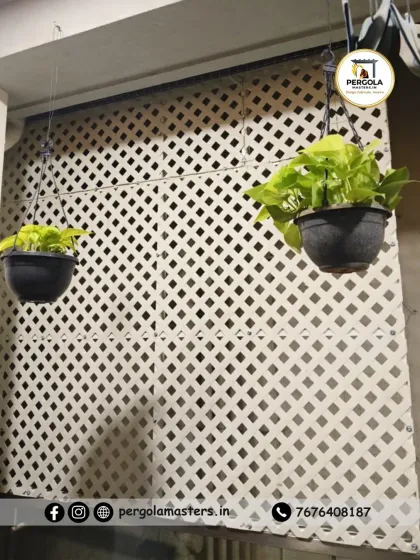 The same white privacy lattice shown with hanging plants. The grid structure is ideal for supporting light climbers or hanging pots, allowing clients to integrate greenery into their privacy screen.