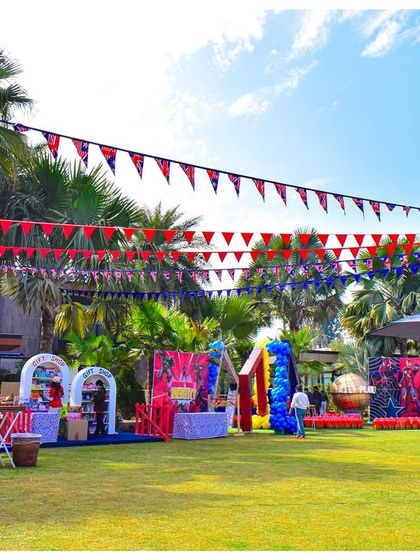 A wide shot of the Avengers party setup on a sunny lawn. You can see the various activity stations, themed banners, and decor elements all coming together to create a cohesive superhero universe.