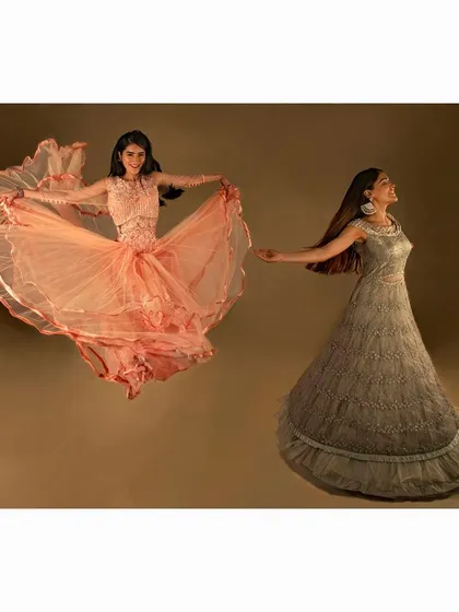 A magical and dynamic studio shot for an Indian fashion brand. The image captures the flowing movement of the gowns, creating a sense of dance and celebration for this ethnic wear collection.
