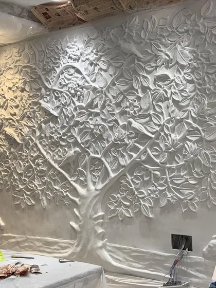 The Kalpavriksha mural in its raw, unpainted state. This behind-the-scenes look reveals the intricate sculpting work before any color is applied.