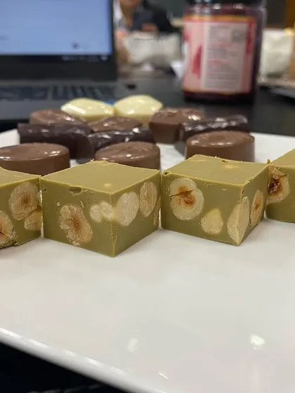 This is our Pistachio Gianduja, cut to show the high density of whole roasted hazelnuts inside. It's a rich, authentic confectionery block that we supply to chocolatiers and pastry chefs for creating premium fillings and desserts.