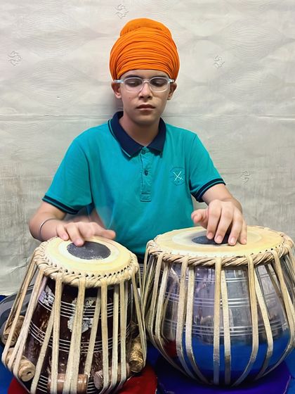 A young student demonstrates proper posture and hand positioning while practicing the tabla.