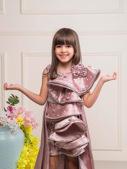 A statement making dusty rose dress with a large, structural ruffle detail on the bodice.