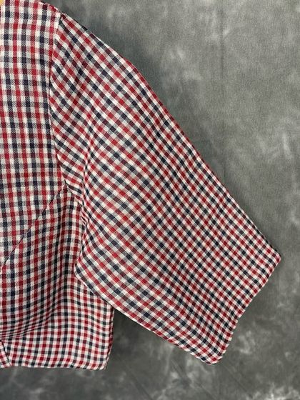A close-up of the multi-color checked cotton fabric. The blend of red, white, and blue in a classic check pattern makes this blouse a timeless piece.