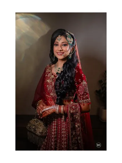 A classic, full-length bridal portrait, with a soft light highlighting the bride's stunning red Nikaah outfit.