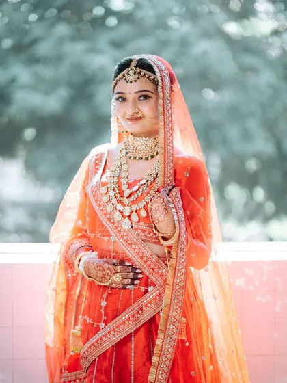 A full-length shot of the bride in her stunning orange and red lehenga, looking absolutely radiant.