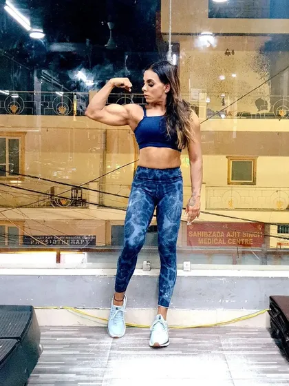 Posing to highlight my bicep peak. I guide my clients on how to structure their meals to fuel their workouts and build impressive muscle features like this.