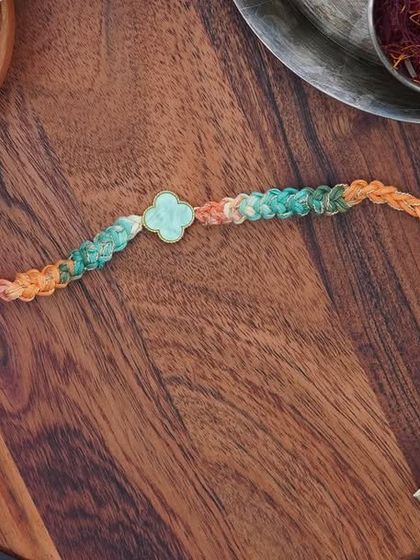 A product shot of the Clover Rakhi, made with a beautiful green and orange variegated yarn.
