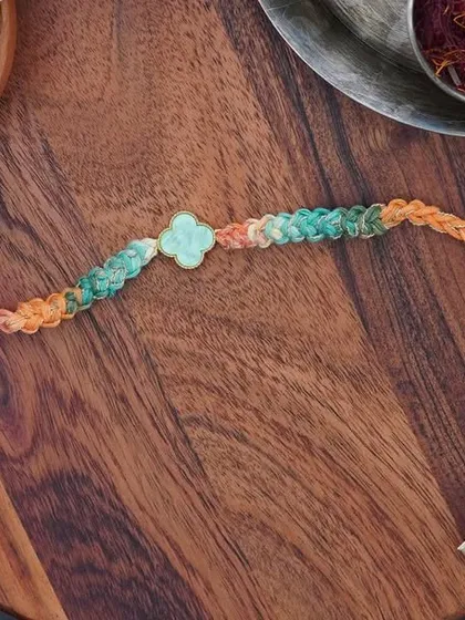 A product shot of the Clover Rakhi, made with a beautiful green and orange variegated yarn.