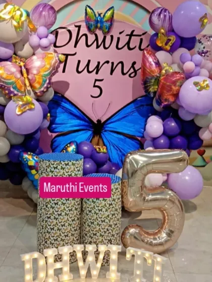 A stunning butterfly-themed party for a 5th birthday. A large blue butterfly is the centerpiece of the backdrop, surrounded by purple and pink balloons and shimmering butterfly foil balloons.
