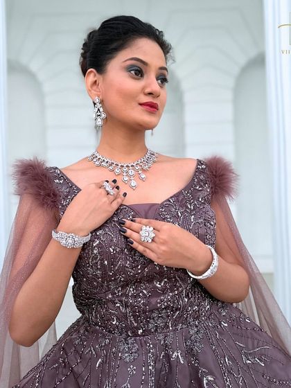 A close-up on the bodice of the mauve gown, showing the intricate beadwork and feather shoulder details.