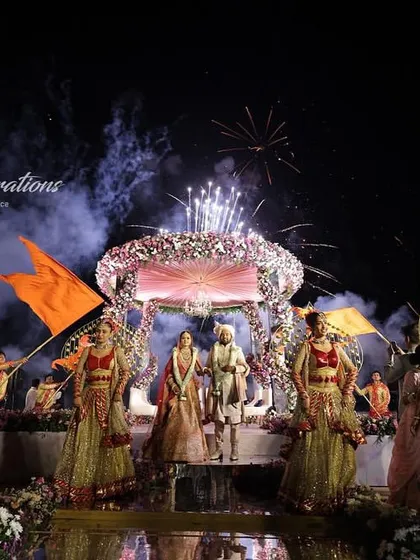 A breathtaking Jaimala at the St. Regis Goa. The couple stands on a stage by the water, framed by dancers and spectacular fireworks lighting up the night sky, creating a truly magical memory.