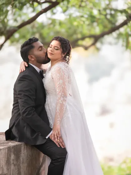 A gentle kiss and a sweet embrace. This candid wedding portrait, taken outdoors with natural light, is full of romance and tenderness.