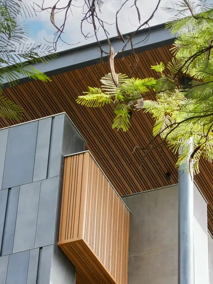 A close-up of the Poorvi Marg facade, showing the beautiful texture of the wood-look aluminum fluting against the sky. The design is chic, elegant, and inviting.