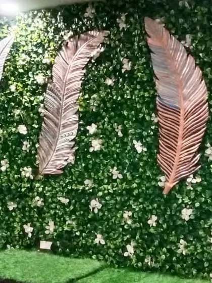 For this installation in Dwarka, I added these large, metallic feather art pieces to the green wall. It's a great example of how you can mix different decor elements with your vertical garden.