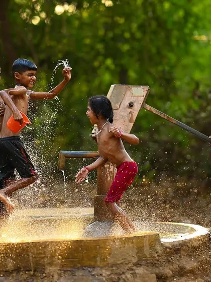 The golden light of the evening sun illuminates the water splashing around the children. This shot highlights the beautiful atmosphere surrounding their energetic play.