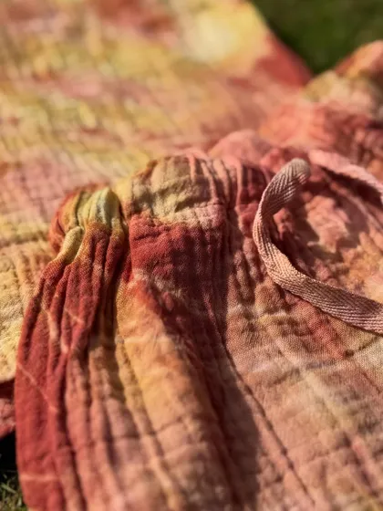A detail shot of the drawstring on the naturally dyed kids' shorts. The blend of red and yellow hues from the herbal dye creates a beautiful, warm pattern.