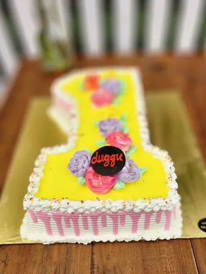 A bright yellow number "1" cake decorated with colorful buttercream flowers. A cheerful and delicious way to celebrate a first birthday.