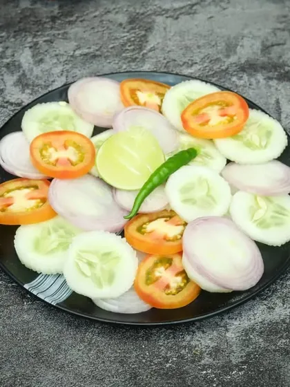 A simple plate of fresh green salad with cucumber, tomato, and onion. It's a healthy and refreshing accompaniment to any meal.