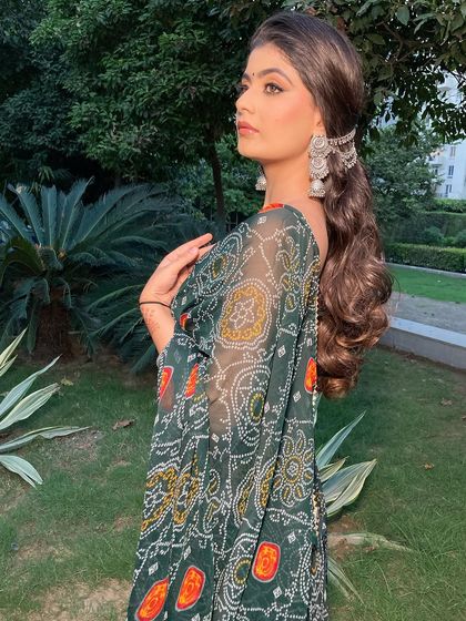 A beautiful outdoor shot of this look. The natural light shows off the soft contour and the beautiful details of her bandhani saree.