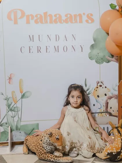A little guest poses at the photo spot for the Mundan ceremony. The personalized sign and adorable stuffed animals made it a popular spot for pictures.