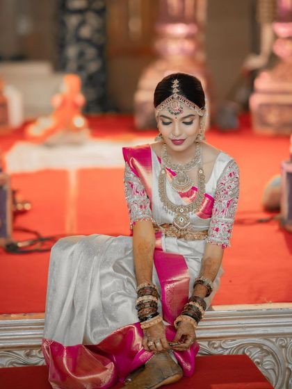 A quiet moment during the ceremony. The bride's makeup is elegant and understated, focusing on enhancing her natural features while complementing the grandeur of her saree and jewellery.