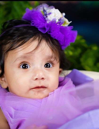 A close-up portrait capturing the beautiful, wide eyes of a toddler in a purple dress.