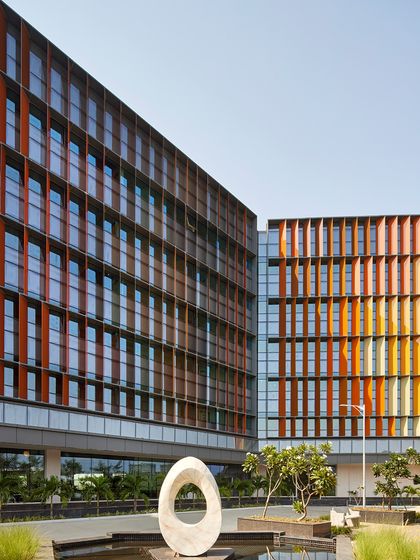 The Infosys Campus in Nagpur features a vibrant facade of solar fins that are both an aesthetic statement and a high-performance climate tool. The landscape is dotted with sculptures and water bodies, creating a stimulating environment that balances art, nature, and technology.