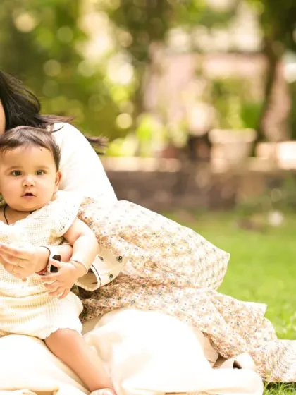 A mother and her baby enjoying a quiet moment together on the grass. The soft, natural light of an outdoor setting is perfect for gentle and intimate portraits.
