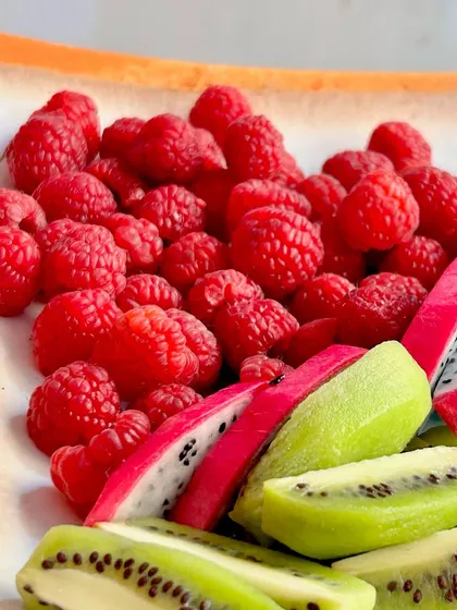 A colourful platter of fresh raspberries, kiwi, and dragon fruit. The vibrant colours and fresh flavours make it a healthy and appealing addition to any dessert table.