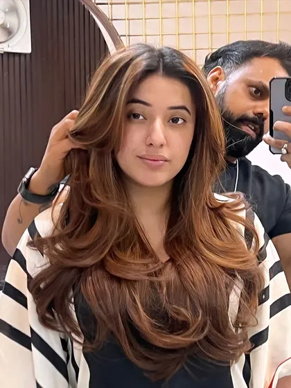 The stylist and client taking a mirror selfie to capture the stunning result of this voluminous layered haircut.