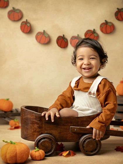 This little pumpkin is all smiles in his autumn-themed setup. The hat is the perfect finishing touch.