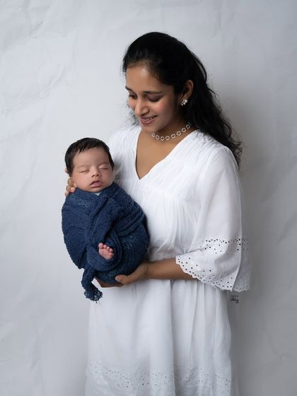 A mother gazes lovingly at her sleeping baby, held close to her heart. This is a simple, elegant portrait that focuses entirely on their special connection.