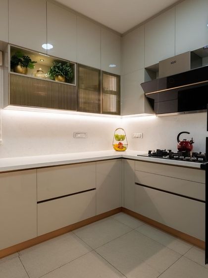 This kitchen design makes everyday life easier by incorporating a mix of opaque, transparent, and translucent storage. The pristine white and beige color palette ensures the space always looks neat, elegant, and pristine.