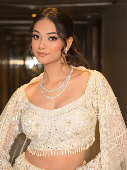 A closer look at the modern bridal glam. The messy ponytail keeps the look fresh and youthful, while the winged eyeliner and defined brows add a touch of sophistication.