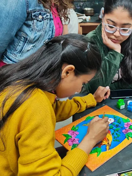 Students working on their clay relief projects, with one receiving guidance from another. We foster a collaborative and supportive learning environment.