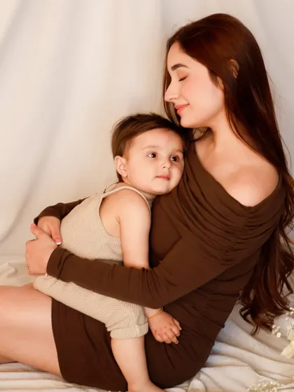 A mother holds her son in a gentle, protective embrace. This tender moment, captured in a soft and simple setting, speaks volumes about the comfort and security of a mother's love.