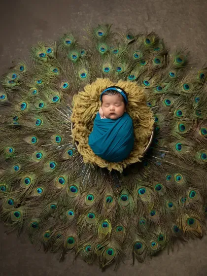 A beautiful overhead shot capturing the symmetry of the peacock feathers arranged around the sleeping baby, creating a stunning visual effect.